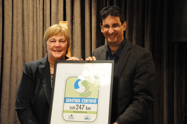 Denise Grenier et Pascal Bigras, respectivement présidente de la Fédération des clubs de motoneigistes du Québec (FCMQ) et directeur général de Nature-Action Québec, lors du dévoilement du panneau de signalisation attestant d'un écosentier certifié.