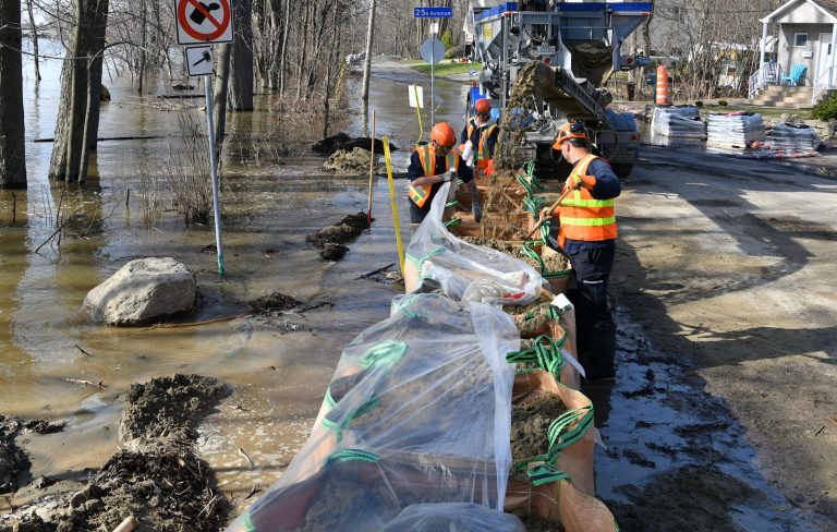 On voit ici des employés de la Ville de Laval ériger une digue pour contrer de possibles inondations de la rivière des Mille Îles à Laval-Ouest.