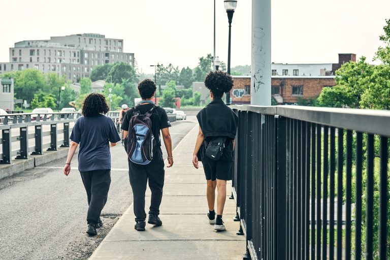 Trois jeunes marchant sur un trottoir à Laval.