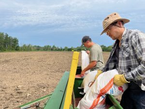 Christophe Girard et Guillaume Beaulieu remplissent le semoir de grains d'orge.(Photo 2M.Media – Geneviève Quessy) 