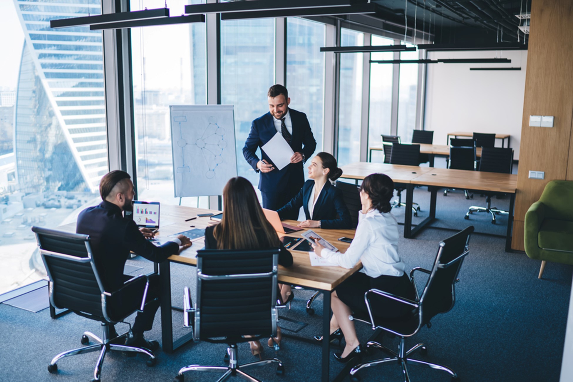 "Image issue des photos pour les entreprises de Depositphotos, représentant plusieurs collègues en réunion autour d’un bureau avec un collaborateur debout près d’un tableau de conférence"