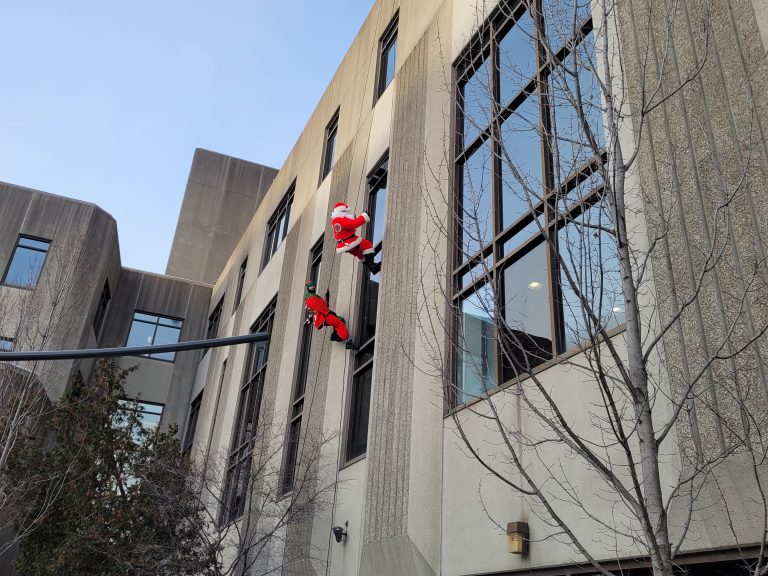 Le père Noël et un de ses lutins descendant sur les murs de la Cité-de-la-Santé pour saluer les patient.e.s de l’extérieur. (Photo 2M.Media – Corinne Prince)