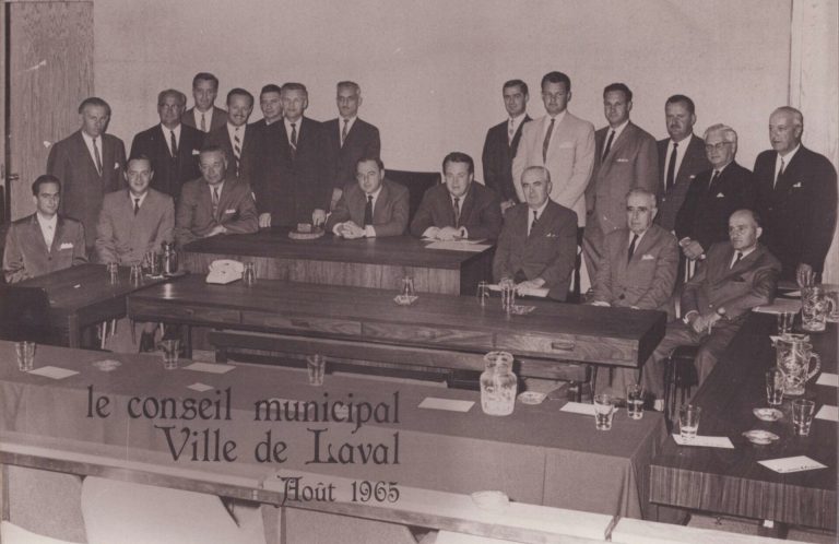 La Ville de Laval a été créée le 6 août 1965. Sur la photo, le premier conseil municipal provisoire formé des 14 maires des ex-municipalités de l’île Jésus fusionnées et de 8 échevins. À l’unanimité, Me Jean-Noël Lavoie est nommé premier maire de Laval.