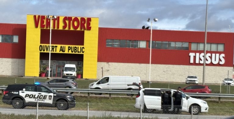 Une opération policière continue de se dérouler sur l’autoroute 13, face au Méga Centre Notre-Dame, le mardi 21 octobre. (Photo 2M.Media – Maggie L’Écuyer)