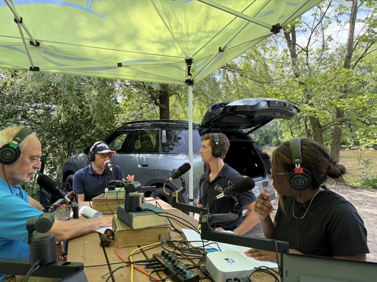 L'ancien ministre des Finances, Carlos Leitão, et le ministre des Relations internationales et de la Francophonie, Christopher Skeete, ont participé en août à un enregistrement radio, alimenté par une voiture électrique, au bord de la rivière des Mille-Îles. (Photo de gracieuseté : L’École fait du Bruit)