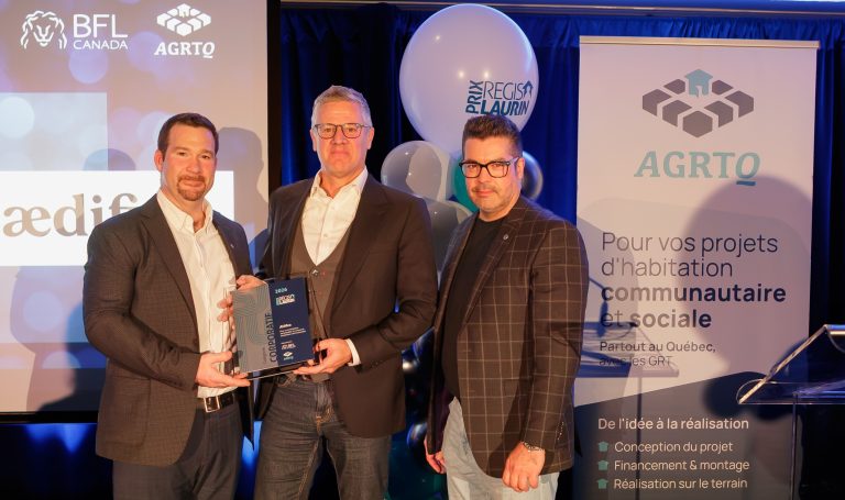 Benoît Laurion et Hugues Daly, respectivement directeur et vice-président architecture chez AEdifica, exhibent fièrement le prix Régis-Laurin – catégorie Corporatif 2026. Cette distinction décernée par l’AGRTQ reconnaît une entreprise dont l'expertise contribue de façon remarquable au développement de l'habitation communautaire et sociale au Québec. Le prix leur a été présenté par Simon Bolduc, spécialiste en immobilier chez BFL Canada.